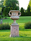 NYMANS  SUSSEX. THE NATIONAL TRUST: URN ON MAIN LAWN WITH TOPIARY YEW HEDGING BEHIND  EVENING LIGHT  JUNE