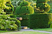 NYMANS  SUSSEX. THE NATIONAL TRUST : VIEW TO TOPIARY  CLIPPED YEW AND ITALIAN MARBLE FOUNTAIN. WALL GARDEN  JUNE  EVENING LIGHT