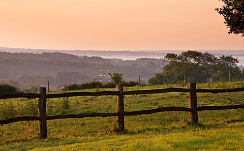 NYMANS__SUSSEX_THE_NATIONAL_TRUST_WOODEN_FENCE_AND_VIEWS_OUT_TO_COUNTRYISED_AT_DAWN__JUNE
