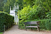 PAINSWICK ROCOCO GARDEN  GLOUCESTERSHIRE: WOODEN BENCH WITH THE EXEDRA IN THE BACKGROUND