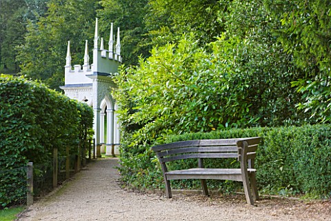PAINSWICK_ROCOCO_GARDEN__GLOUCESTERSHIRE_WOODEN_BENCH_WITH_THE_EXEDRA_IN_THE_BACKGROUND