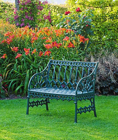 PECKOVER_HOUSE__WISBECH__CAMBRIDGESHIRE_THE_NATIONAL_TRUST__METAL_SEATBENCH_ON_LAWN_BY_RED_BORDER_WI