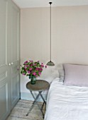 TWIG HUTCHINSON HOUSE  LONDON: BEDROOM WITH BED  BEDSIDE LIGHT AND SMALL TABLE WITH PINK CLEMATIS IN GLASS VASE
