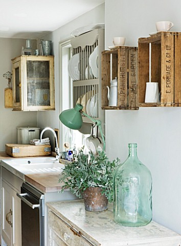 TWIG_HUTCHINSON_HOUSE__LONDON_KITCHEN_WITH_GREEN_GLASS_JAR_AND_FRUIT_BOXES_ON_WALL