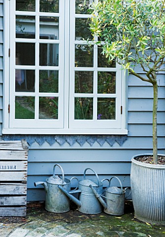 TWIG_HUTCHINSON_HOUSE__LONDON_BLUE_SHED_WITH_BLUE_METAL_WATERING_CANS_BENEATH_WINDOW