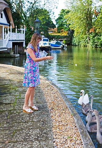THE_BOAT_HOUSE_DESIGNER_ARLETTE_GARCIA__OWNER_JUDY_TAYLOR_FEEDING_SWANS_ON_THE_RIVER_THAMES_FROM_HER
