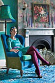 VELVET ECCENTRIC: HANNAH BAUD SITS IN A VELVET BLUE CHAIR BY VELVET ECCENTRIC IN THE DRAWING ROOM