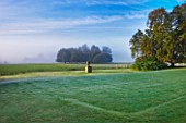 RAGLEY HALL GARDEN  WARWICKSHIRE: STATUE AND PARKLAND IN MIST - EARLY MORNING