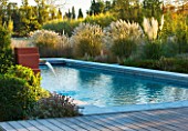 AFRICAN GARDEN  PROVENCE  FRANCE: DESIGNER DOMINIQUE LAFOURCADE: WATER FOUNTAINS SPURTING INTO THE SWIMMING POOL WITH PAMPAS GRASS  EVENING LIGHT
