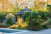 AFRICAN GARDEN  PROVENCE  FRANCE: DESIGNER DOMINIQUE LAFOURCADE: PAMPAS GRASS AND A THATCHED HUT WITH BLACKENED WOODEN STAKE FENCING