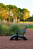 AFRICAN GARDEN  PROVENCE  FRANCE: DESIGNER DOMINIQUE LAFOURCADE: PAMPAS GRASS WITH BLACK LOUNGER/ SEAT ON ROSE COLOURED GRAVEL