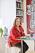 SHELLEY VON STRUNCKEL APARTMENT  LONDON: SHELLEY AT HER WRITING DESK - TWO HABITAT TABLES PUSHED TOGETHER TO FORM A SQUARE