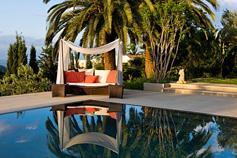 DESIGNER_JAMES_BASSON_SCAPE_DESIGN_FRANCE_SKY_REFLECTED_IN_SWIMMING_POOL_WITH_CANOPY_OVER_SUN_LOUNGE