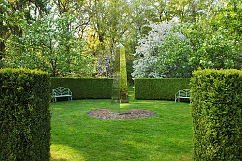 DODDINGTON_PLACE_GARDENS__KENT_BENCHES_AND_BLOSSOM_IN_THE_SPRING_GARDEN_WITH_MIRRORED_OBELISK_BY_DAV