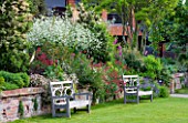 GLYNDEBOURNE, EAST SUSSEX: VIEW TO THE OPERA HOUSE OVER THE DOUBLE HERBACEOUS BORDERS WITH WHITE CRAMBE CORDIFOLIA - TWO WOODEN BENCHES / SEATS ON LAWN