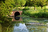 GLYNDEBOURNE, EAST SUSSEX: VIEW ACROSS LAKE TO MEADOW AND BRICK BRIDGE - WATER, POOL, TRANQUIL, PEACEFUL, COUNTRY GARDEN, LANDSCAPE