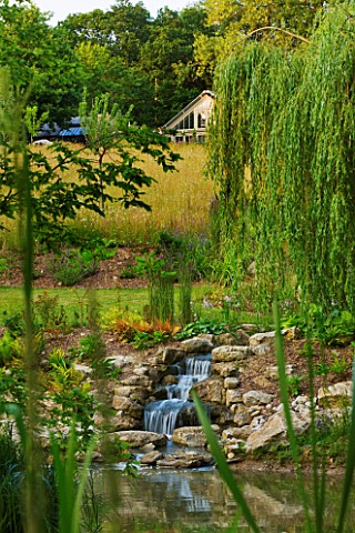 GARDEN_IN_KENT_DESIGNED_BY_BELLA_WHITELEY_VIEW_OF_WILDFOWER_MEADOW_AND_STREAM_FROM_LAKE_POOL_WATER_P