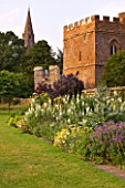 BROUGHTON CASTLE, OXFORDSHIRE: HERBACEOUS BORDER ALONG THE GARDEN WALL WITH THE GATEHOUSE AND CHURCH BEHIND - FLOWERS, SUMMER, FLOWERING, ENGLISH GARDEN, COUNTRY GARDEN