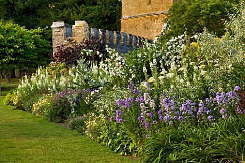 BROUGHTON_CASTLE_OXFORDSHIRE_HERBACEOUS_BORDER_ALONG_THE_GARDEN_WALL_WITH_THE_GATEHOUSE_BEHIND__FLOW