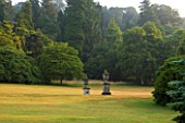KILLERTON  DEVON: THE NATIONAL TRUST - VIEW ACROSS LAWN TO URNS ON PEDESTALS AND WOODLAND BEYOND