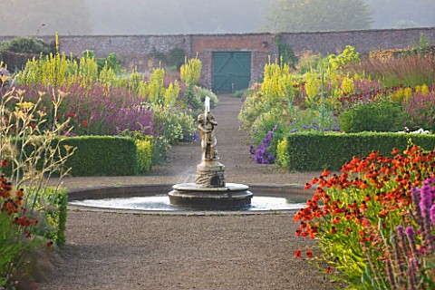 HELMSLEY_WALLED_GARDEN__YORKSHIRE_THE_HERBACEOUS_BORDER_IN_JULY_WITH_FOUNTAIN__HELENIUMS_AND_VERBASC