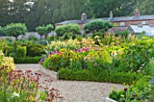 SLEDMERE HOUSE GARDEN, YORKSHIRE: BORDER BESIDE THE GREENHOUSE IN THE WALLED GARDEN - SUNSET, SUNFLOWERS, FLOWERS, FLOWERING, SUMMER, GRAVEL, PATH, GLASSHOUSE