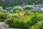 SLEDMERE HOUSE GARDEN, YORKSHIRE: BORDER BESIDE THE GREENHOUSE IN THE WALLED GARDEN - SUNSET, SUNFLOWERS, FLOWERS, FLOWERING, SUMMER, GRAVEL, PATH, GLASSHOUSE