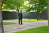 GLYNDEBOURNE, EAST SUSSEX: THE FIGARO GARDEN WITH LAWN AND PAVING AND BRONZE BY SEAN HENRY - STANDING MAN - MIST, FOG, SCULPTURE