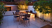 FULHAM GARDEN DESIGNED BY AMIR SCHLEZINGER - MY LANDSCAPES: MINIMALIST GARDEN LIT UP AT NIGHT -  ACER ACONITIFOLIUM  TABLE AND CHAIRS  PATIO  BUDDHA HEADS  WOODEN BENCH  BAMBOO