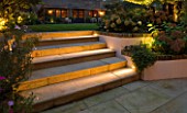 NOTTING HILL HOUSE, LONDON. GARDEN DESIGN BY BUTTER WAKEFIELD. STONE STEPS/STAIRS WITH LIGHTING AND RAISED RENDERED BEDS WITH HYDRANGEAS. UPLIGHTING,EVENING,LIT,NIGHT,DUSK,GLOW