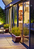 ROOF GARDEN IN SHOREDITCH  LONDON  DESIGNED BY AMIR SCHLEZINGER OF MY LANDSCAPES: DECKING AND CONTAINERS WITH LIBERTIA GOLDFINGER  LIT UP AT NIGHT  LIGHTING