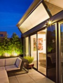 ROOF GARDEN IN SHOREDITCH  LONDON  DESIGNED BY AMIR SCHLEZINGER OF MY LANDSCAPES: PATIO WITH LOUNGER  PHYLLOSTACHYS NIGRA   LIT UP AT NIGHT  LIGHTING