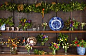 COMMON FARM FLOWERS. SOMERSET: DRESSER IN COMMON FARM FLOWER ROOM. BERRIED HOLLY  ROSEHIPS  SCILLY ISLES SCENTED TAZETTA NARCISSI  ANEMONE DE CAEN  IVY AND HYDRANGEA HEAD GARLANDS.