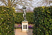 ANGLESEY ABBEY  CAMBRIDGESHIRE: STATUE - THE BOY WITH RAISED ARMS IN A SMALL ENCLOSED GARDEN