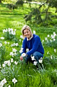 EASTON WALLED GARDEN  LINCOLNSHIRE:  URSULA CHOLMELY IN THE MEADOW SURROUNDED BY NARCISSUS POETICUS RECURVUS - PHEASANTS EYE NARCISSUS - DAFFODILS  WHITE FLOWERS. SPRING