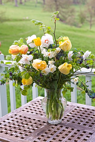 EASTON_WALLED_GARDEN__LINCOLNSHIRE_SPRING_FLORAL_ARRANGEMENT_IN_VASE_ON_OUTSIDE_TABLE_WITH_TULIPS__N