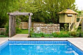 ARALIA GARDEN DESIGN - PATRICIA FOX: WEDNESDAY HOUSE: SWIMMING POOL AND WOODEN PERGOLA, TREE HOUSE IN BACKGROUND