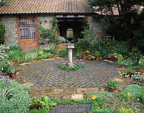 OCTAGONAL_COURTYARD_GARDEN_WITH_BRICK_PAVING__CONTAINERS_AND_BIRDBATH_IN_FRONT_OF_OLD_COACH_HOUSE_TU
