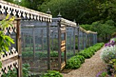 ROCKCLIFFE HOUSE  GLOUCESTERSHIRE: PATH THROUGH THE WALLED KITCHEN GARDEN WITH ORNATE FRETWORK FRUIT CAGES