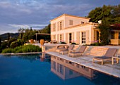CORFU, GREECE - THE KASSIOPIA ESTATE: VIEW OF THE VILLA, STONE TERRACE WITH SEATING AREA  AND SWIMMING POOL IN THE EVENING