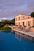 CORFU, GREECE - THE KASSIOPIA ESTATE: VIEW OF THE VILLA, STONE TERRACE WITH SEATING AREA  AND SWIMMING POOL IN THE EVENING