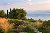 CORFU, GREECE - THE KASSIOPIA ESTATE:VIEW OUT TO SEA FROM THE TERRACE WITH PATH AND PLANTING SCHEME OF STIPA TENUISSIMA AND TULBAGHIA VIOLACEA