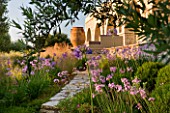 CORFU, GREECE - THE KASSIOPIA ESTATE: VIEW LOOKING UP TOWARDS VILLA WITH STONE URN, PATH AND PINK FLOWERS OF TULBAGHIA VIOLACEA