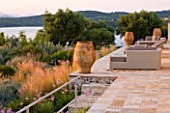 CORFU, GREECE - THE KASSIOPIA ESTATE: THE SUN TERRACE LOOKING OUT ONTO THE GARDEN WITH SEATING AREA, TERRACOTTA URNS AND VIEW OUT TO SEA