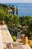 CORFU, GREECE - THE KASSIOPIA ESTATE: VIEW LOOKING DOWN ONTO THE GARDEN AND OUT TO SEA WITH STONE PATH, OLIVE TREES AND CYPRESS TREES