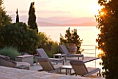 CORFU, GREECE - THE KASSIOPIA ESTATE: EVENING LIGHT - STONE TERRACE WITH SEATING AREA LOOKING OUT TO SEA AT DUSK