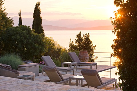 CORFU_GREECE__THE_KASSIOPIA_ESTATE_EVENING_LIGHT__STONE_TERRACE_WITH_SEATING_AREA_LOOKING_OUT_TO_SEA