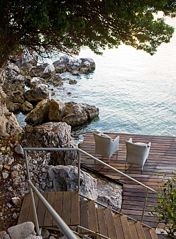 CORFU_GREECE__THE_KASSIOPIA_ESTATE_VIEW_OF_STEPS_LEADING_DOWN_ONTO_DECKED_SEATING_AREA_IN_THE_BAY_WI