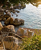 CORFU, GREECE - THE KASSIOPIA ESTATE: VIEW OF STEPS LEADING DOWN ONTO DECKED SEATING AREA IN THE BAY WITH VIEW OUT TO SEA. A PLACE TO SIT.