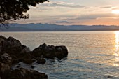 CORFU, GREECE - THE KASSIOPIA ESTATE: VIEW OF THE BAY LOOKING OUT TO SEA AT SUNSET WITH ALBANIAN MOUNTAINS IN THE DISTANCE